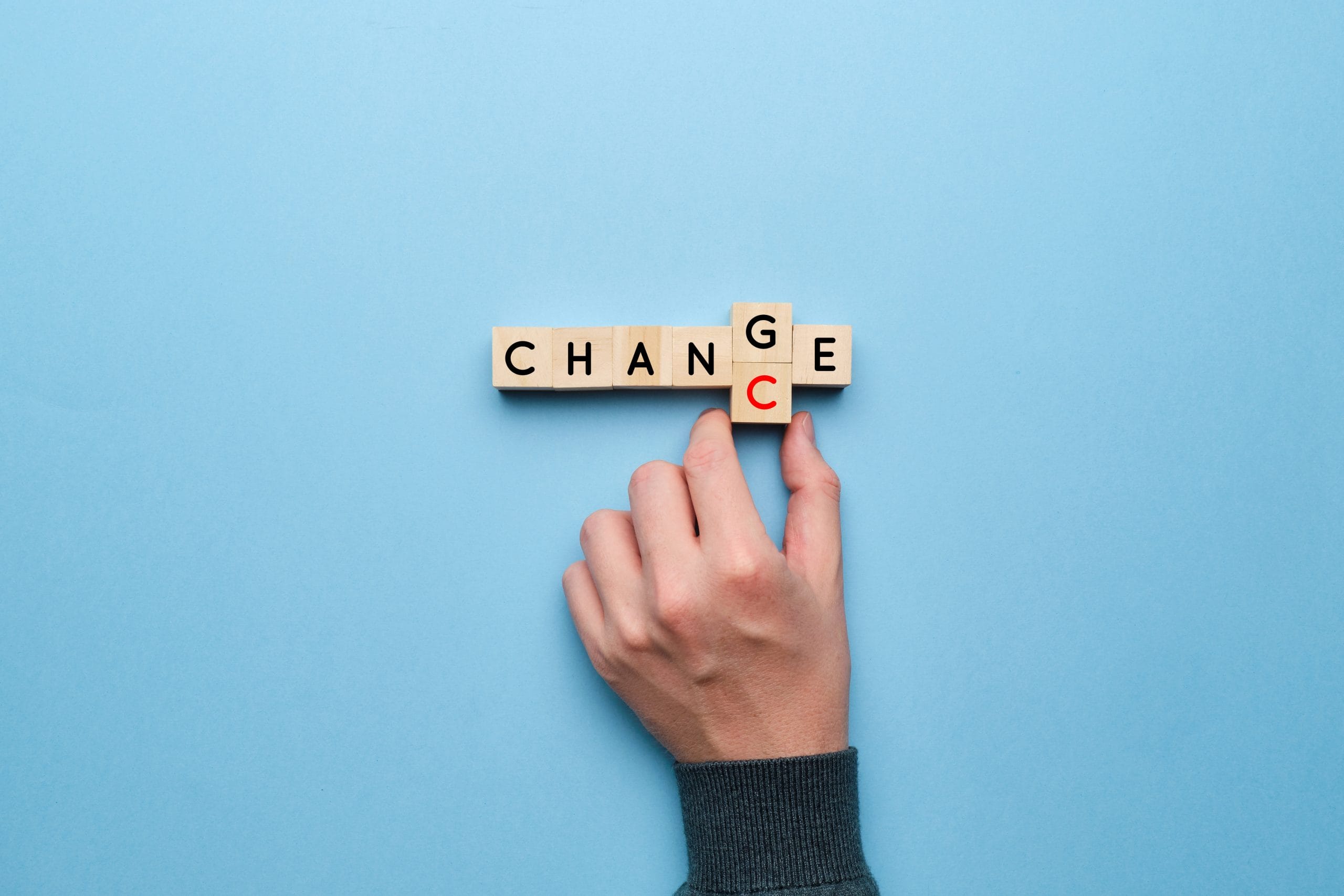 The concept of change and chance. Hand picks up letters on a yellow background.